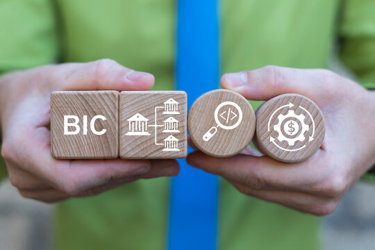 Business person holding wooden blocks with icons sees the abbreviation BIC. BIC Bank Identifier Code Finance Banking Business Concept. Financial systems, global transactions, secure banking processes.