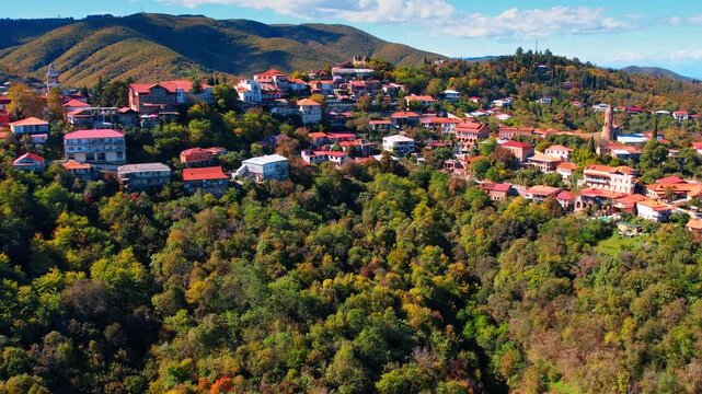 Multiple lovely houses located on the rocks among the lush greenery. Beautiful village in the Caucasian Mountains, Georgia on sunny day.