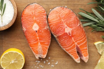 Pieces of salmon fillet with spices and lemon on wooden table, flat lay