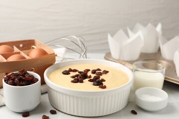 Ingredients for making muffins, whisk and cupcake tray on white table, closeup