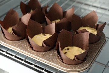 Making muffins. Cupcake tray with dough in oven, closeup