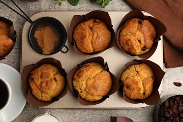 Naklejka premium Tasty muffins with raisins, mint and coffee on grey table, flay lay