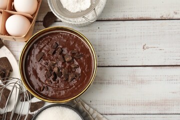 Ingredients for making muffins and whisk on white wooden table, flat lay. Space for text