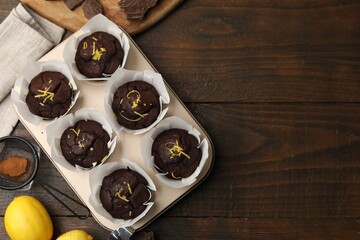 Tasty chocolate muffins with lemon zest on wooden table, flat lay. Space for text