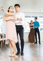 Naklejka premium Couple of young guy and young woman dancing waltz in studio