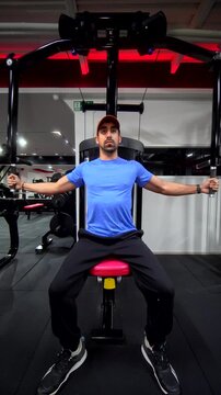 Front View of a Man Performing Pec Deck Chest Fly &ndash; Vertical Chest Workout