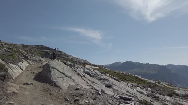 Norway. Hiking to Trolltunga. Hiking Trolltunga on a warm, sunny day in Norway. Busy trail full of travelers and stunning views over Ringedalsvatnet captured from first-person view.