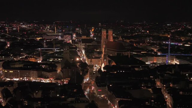 Aerial Night View ueber Muenchen: Die Frauenkirche und das Neue Rathaus erscheinen hell beleuchtet, waehrend der Weihnachtsbaum und der Weihnachtsmarkt am Marienplatz festlich glitzern