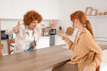 Angry mother squabbling with her teenage daughter in kitchen