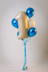 Photo of the number one made of foil with balloons for a boy's children's birthday on a white background in a cyclorama photo studio.