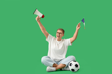 Fototapeta premium Female soccer fan with megaphone and French flag sitting on green background
