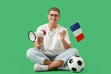 Female soccer fan with megaphone and French flag sitting on green background