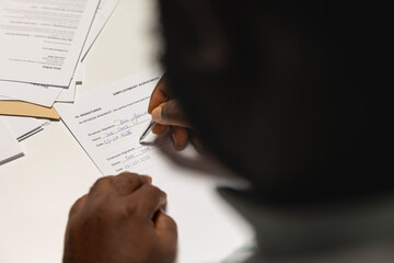 Close up of candidate signing a job contract after successful interview and HR approval, recruiter and applicant sit together to review the legal terms of employment. New professional beginning.
