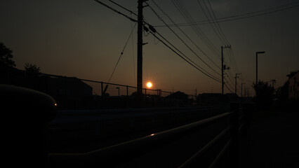 Sunset over Cityscape with Power Lines and Utility Poles in Silhouette / 電線と電柱のシルエット越しに沈む夕日の街並み