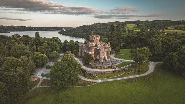 Aerial view of a historic castle on a hill overlooking a lake at dusk - Powered by Adobe