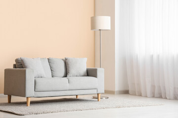 Interior of light living room with grey sofa, floor lamp and window