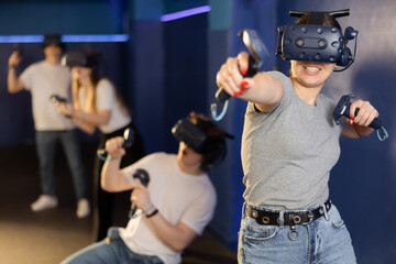 Young woman with handheld controllers in hands clearly excited and engaged in virtual world experiencing through VR glasses covering face. Concept of immersion and interactivity in game