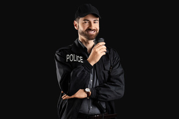 Obraz premium Happy male police officer with cup of coffee on black background