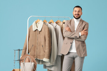 Male stylist with warm clothes on blue background