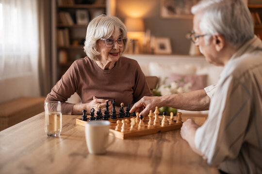 Warm Moment With Elderly Couple Playing Chess At Home, Cozy Living Room