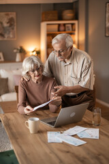 Obraz na płótnie Canvas Elderly Couple Reviews Bills and Finances on Laptop at Home, Planning Retirement Together