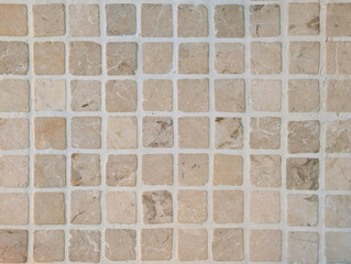 Natural stone mosaic tile texture. Square tesserae in beige, cream and brown with veining and light-colored grout. Small marble slab cladding for interior wall, bathroom, kitchen, patio, pool. 