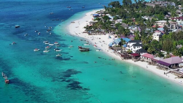 4k aerial video footage of Nungwi Beach -  popular tourist destination- with people on the white sand beach and in the turquoise water, located in Nungwi village in most northern part of Zanzibar