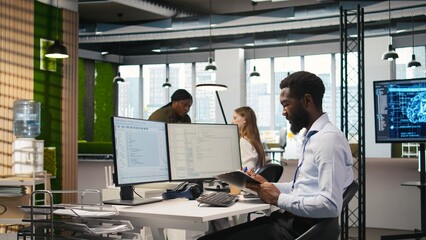 Admin in tech startup office using PC, compiling software patches to fix bugs, troubleshooting backend operations. IT expert running diagnostics, resolving system crashes via terminal, camera A