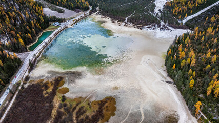 aerial view of mountain landscape and D&uuml;rrensee, a picturesque mountain lake (almost dried out) situated  in the H&ouml;hlensteintal in the Sexten Dolomites in South Tyrol, surrounded by autumn forest