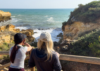 Fototapeta premium mother and daughter tourist hiking on trail along Atlantic ocean in Coast in Algarve in Portugal 