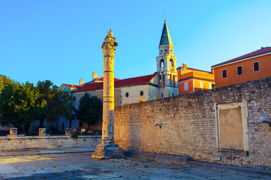 Roman Forum in Zadar, Croatia, featuring ancient "Pillar of Shame" in and Baroque Orthodox Church of Saint Elijah Prophet. Roman ruins, medieval punishment history, 18th-century religious architecture
