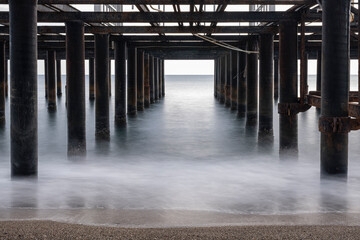 Underneath view of abandoned wooden pier structure. Empty pier frame seen from below. Aging pier...
