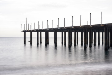 Obraz premium Old Pier Standing Over Calm Sea Water. Abandoned Pier Over the Sea. Deserted Wooden Pier in Seascape. Lonely Abandoned Dock Extending into the Ocean.