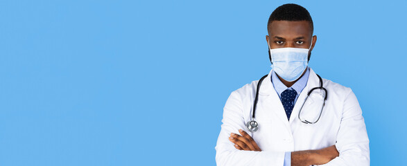 A medical professional stands with arms crossed, wearing a white coat and a mask. The blue background highlights his confident expression and medical attire, symbolizing health and care.