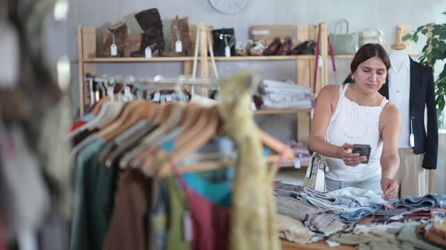 Latin female customer scans QR code on trousers label, activates discount code, and registers purchase in clients personal account.