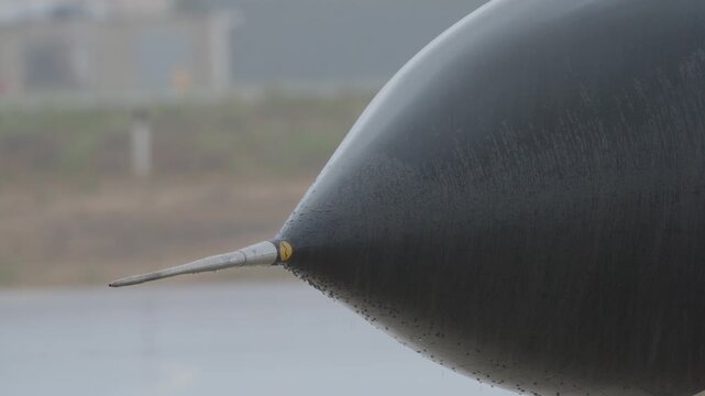 Close up view of military jet nose radome and sensor probe with rain droplets highlighting aircraft surface and design