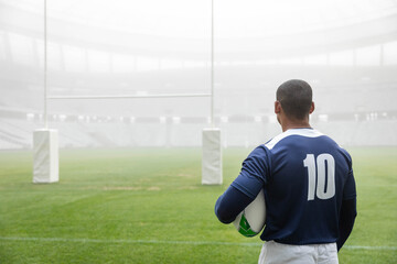 Number 10 jersey is holding rugby ball on grass pitch near padded goalposts during mist