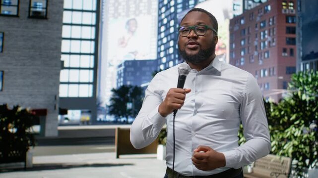 Journalist and communicator conducting on air segment on city street, holding microphone and sharing breaking news information. Dedicated media career presence, field work. Camera A.