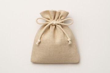 Small beige linen drawstring pouch with cotton rope tie isolated on white background, minimalist reusable fabric bag