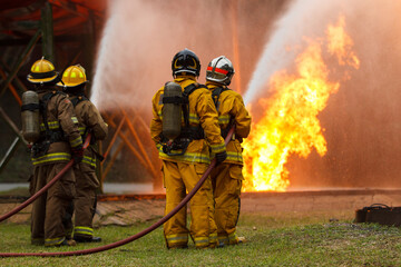 Naklejka premium Firefighters using hose to control flames during emergency response