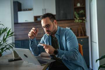 Man making online payment with credit card on laptop