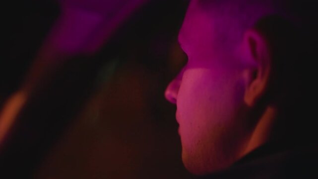 white man driver illuminated by neon side profile in car with purple magenta lighting, reflective window and focused expression, rideshare operator on late shift, cinematic shallow depth and intimate