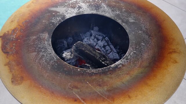 hot embers glow beneath metal grill plate as heat rises