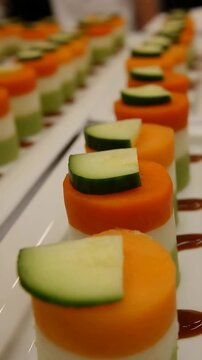 Vibrant Layered Vegetable Appetizers with Fresh Cucumber Slices on a White Platter.