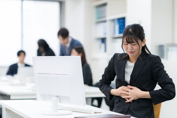 Fototapeta premium オフィスで体調が悪い若いビジネスウーマン