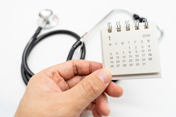 Hand holding desk calendar set to JANUARY 2026. Doctor Appointment Schedule and Annual Health Checkup Reminder. Preventive medicine, healthcare planning, doctor visits, and timely examinations.