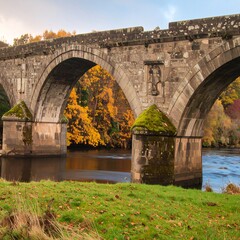 Fototapeta premium Stone arch bridge over a river, autumn foliage