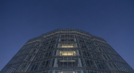 Modern glass skyscraper facade rises against a deep blue twilight sky dotted with stars