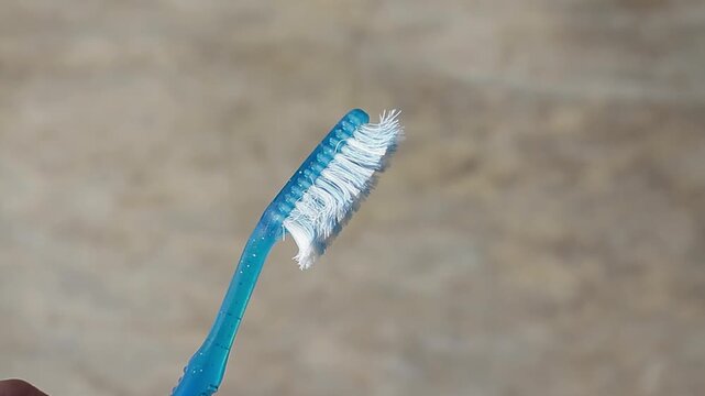 Macro shot of a used blue plastic toothbrush with its bristles visibly frayed and spread out. Symbolizing poor dental hygiene and the necessity of replacement.