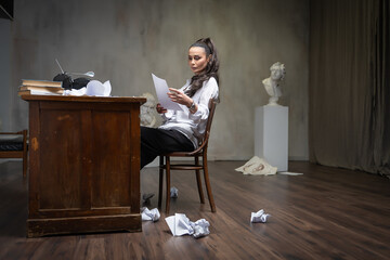 A female writer works at a typewriter, writing an essay.